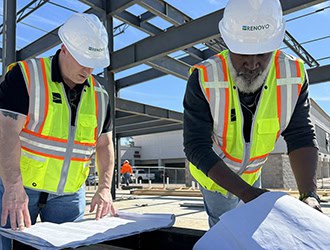 Two men reviewing schematics at a build site