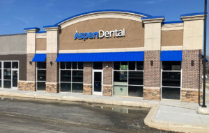 Aspen Dental facade showing the bright blue small awnings, AspenDental signage, windows, and doors.